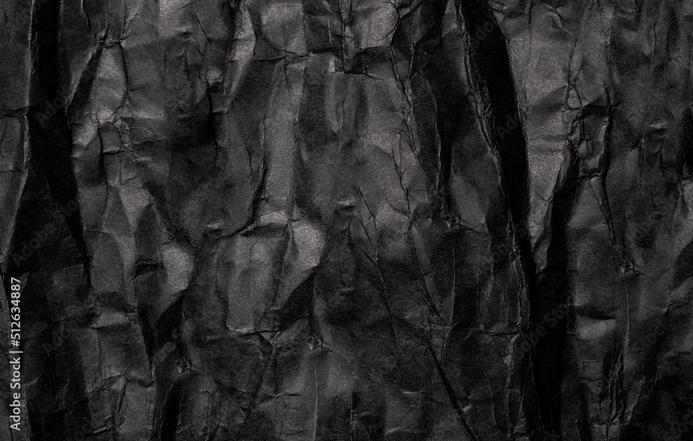 Black crumpled paper texture in low light background. Old grunge black paper backdrop. Wrinkled paper. Copy space for text, design art work.