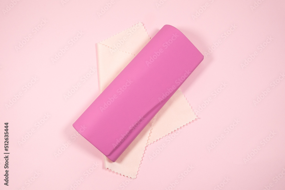 Pink frame womens glasses with glasses cleaning cloth and case on a pink background. Pink frame womens glasses with glasses cleaning cloth and case on a pink background.