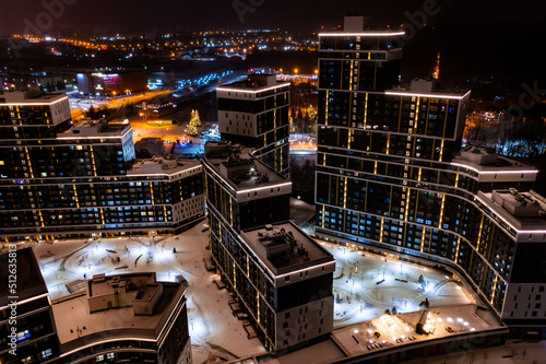 An aerial view of new residential area with apartment buildings and shopping mall lit up by evening illumination