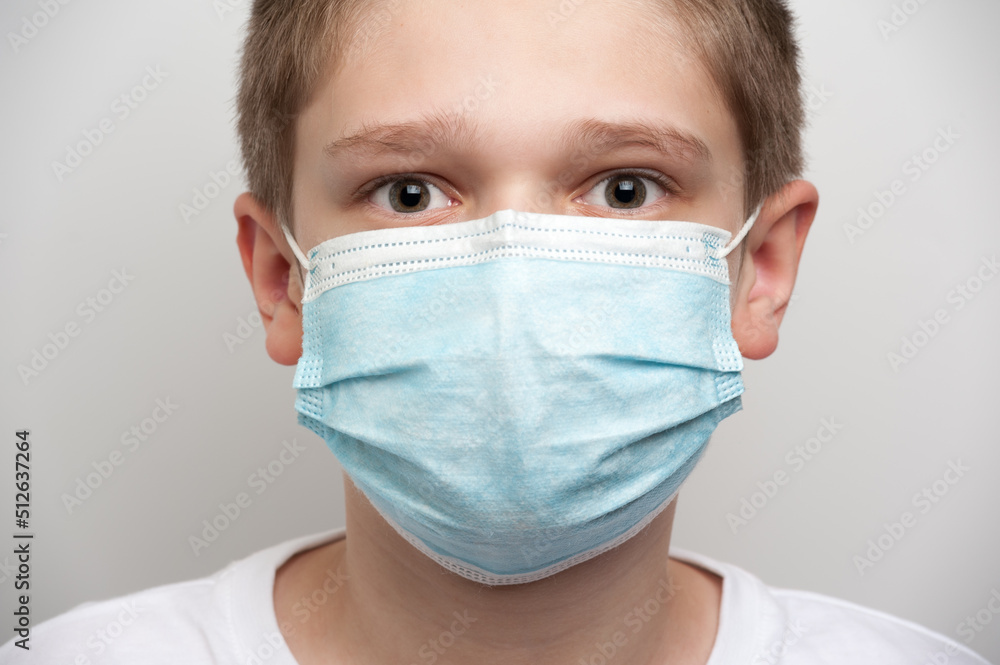 The portrait of a caucasian boy with deep eyes and a medical mask covering his face The portrait of a caucasian boy with deep eyes and a medical mask covering his face