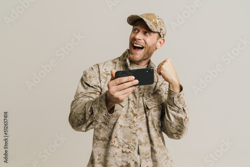 White military man gesturing while playing game on cellphone