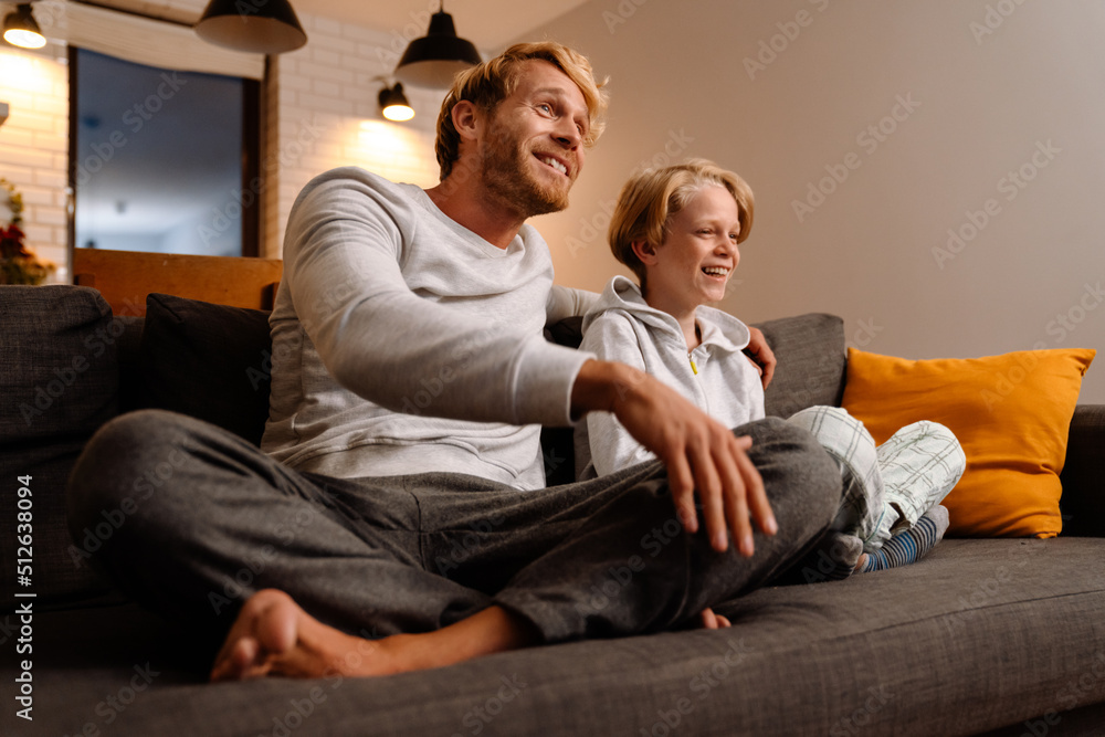 Ginger father and son laughing together while resting on couch