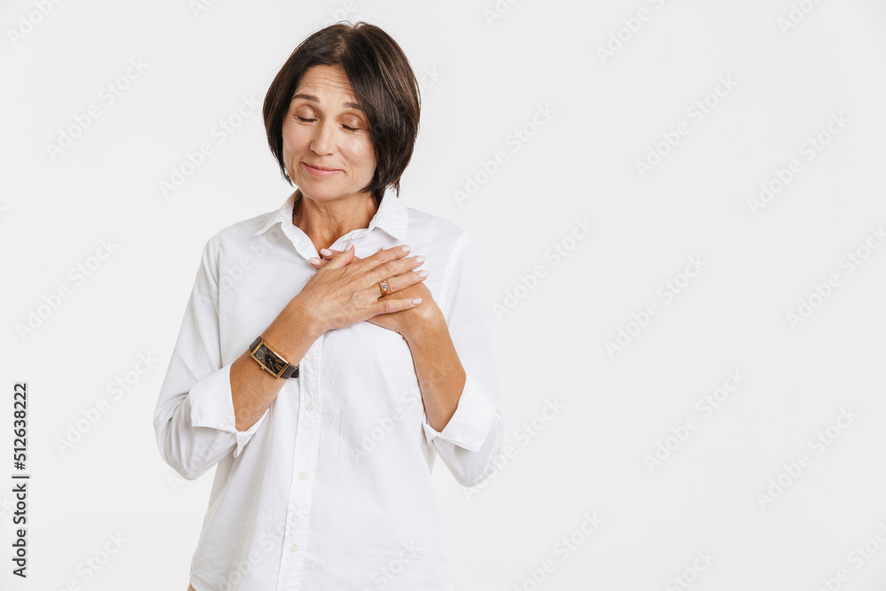 Mature brunette woman smiling and holding hands on her chest Mature brunette woman smiling and holding hands on her chest