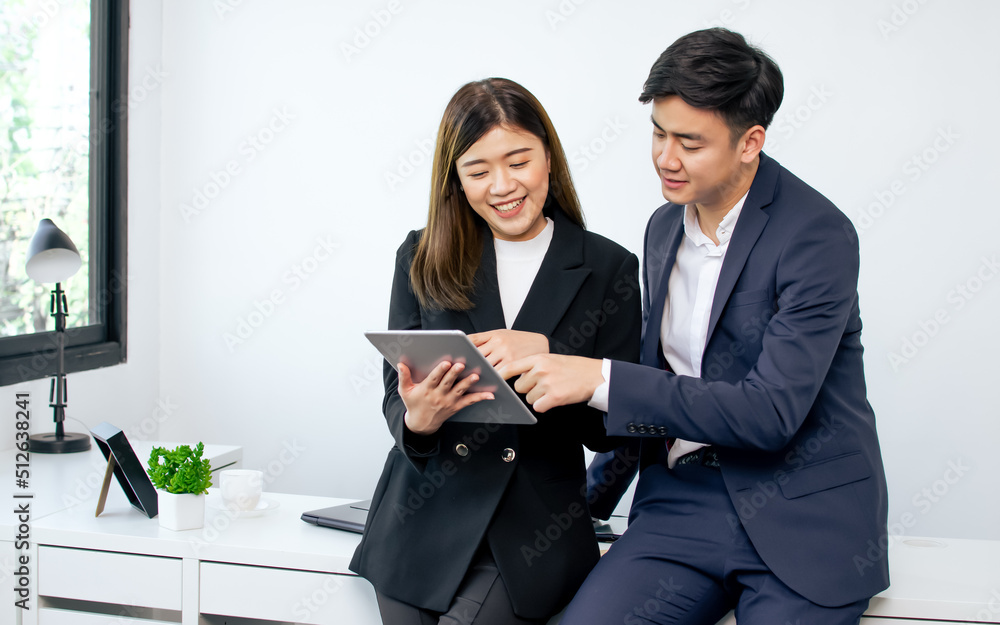 Asian business handsome man and beautiful woman wearing formal suits and white shirt, working, discussing, presenting, touching tablet screen and smiling with happiness in indoor office. Asian business handsome man and beautiful woman wearing formal suits and white shirt, working, discussing, presenting, touching tablet screen and smiling with happiness in indoor office.