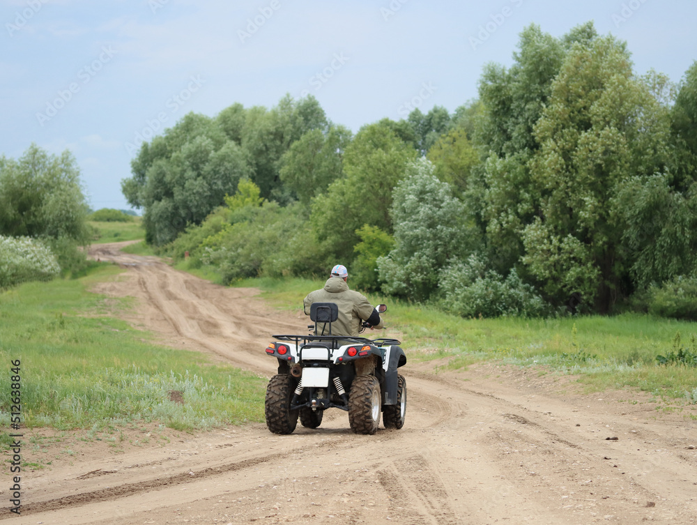 Obraz premium Quad bike ride on a field road on a summer evening