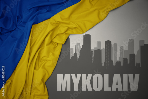 Принти на полотні abstract silhouette of the city with text Mykolaiv near waving national flag of ukraine on a gray background