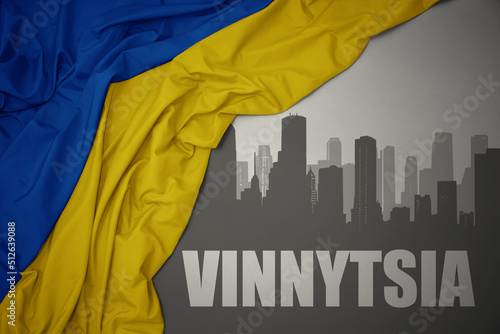 Fotografi abstract silhouette of the city with text Vinnytsia near waving national flag of ukraine on a gray background