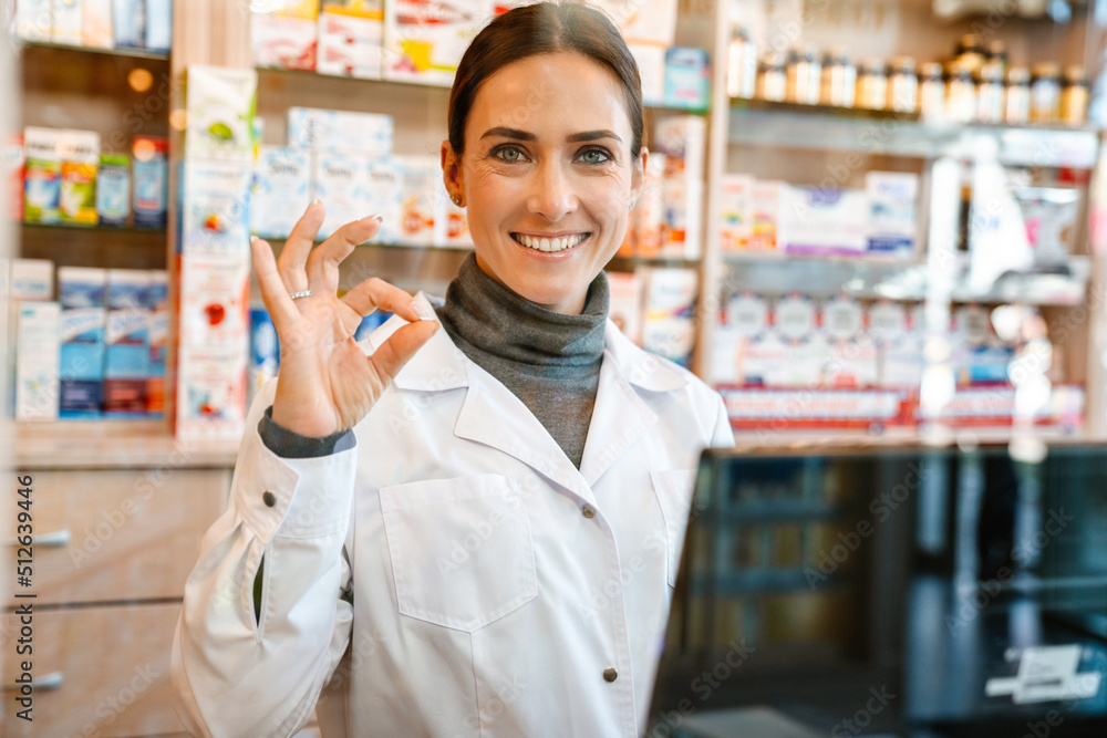 White apothecary gesturing while working with till at pharmacy