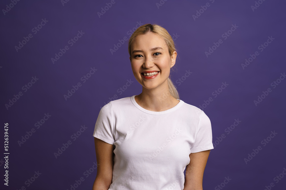 Smiling young blonde asian woman standing isolated Smiling young blonde asian woman standing isolated