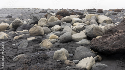 Large smooth boulders in black sand beach in Iceland