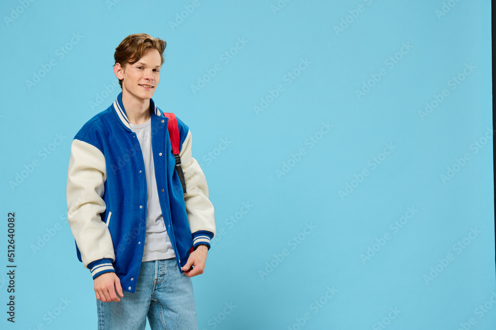 Naklejka premium student with a backpack on his shoulder posing on a blue background