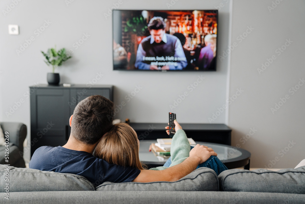Young white man and woman sitting on sofa and watching TV at home Young white man and woman sitting on sofa and watching TV at home