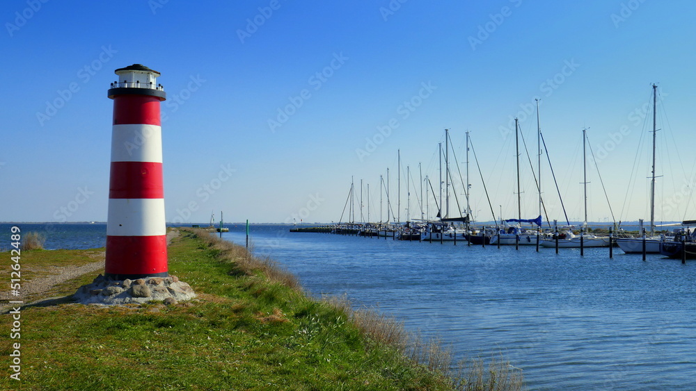 dekorativer Leuchtturm steht auf Fehmarn im Dorf Orth  am Hafen mit Segelbooten unter blauem Himmel