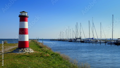 dekorativer Leuchtturm steht auf Fehmarn im Dorf Orth am Hafen mit Segelbooten unter blauem Himmel