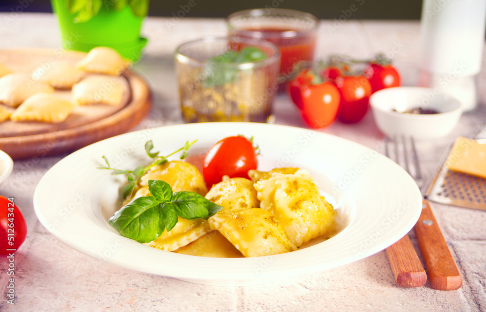 Homemade traditional italian ravioli pasta with basil and tomato cherry vegetables on the wooden table Homemade traditional italian ravioli pasta with basil and tomato cherry vegetables on the wooden table