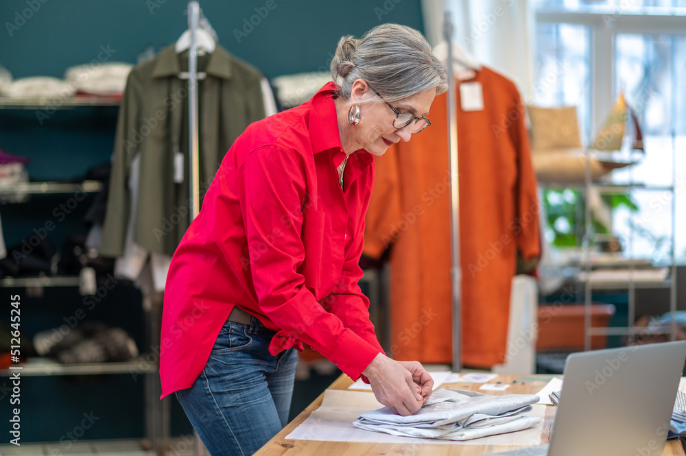 Woman standing sideways to camera packing clothes Woman standing sideways to camera packing clothes