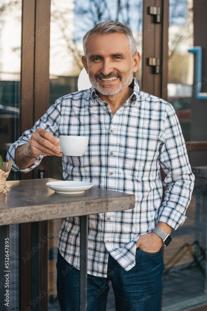 Man drinking coffee outdoors smiling at camera Man drinking coffee outdoors smiling at camera