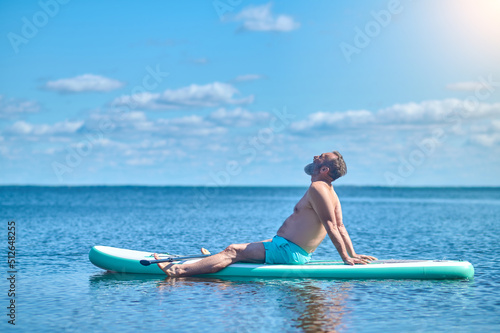 Man sitting meditating on paddle board on water