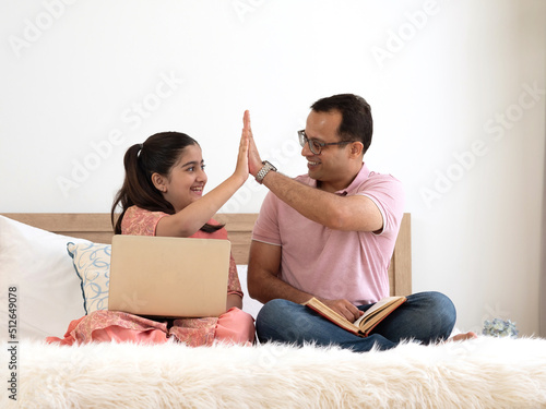 Hands of happy Indian father and pretty daughter giving high five, tag hands with happiness for the achievement and success. Lifestyle, education concept.
