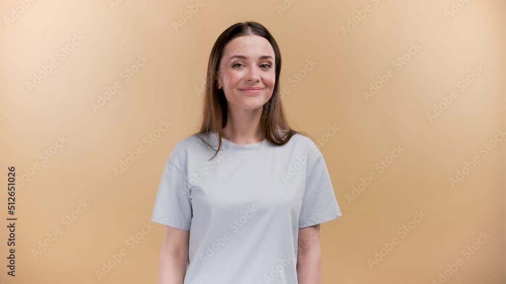 Cheerful young caucasian woman in white t-shirt isolated on beige background. Doing phone gesture says call me back smiling looking at the camera. Cheerful young caucasian woman in white t-shirt isolated on beige background. Doing phone gesture says call me back smiling looking at the camera.