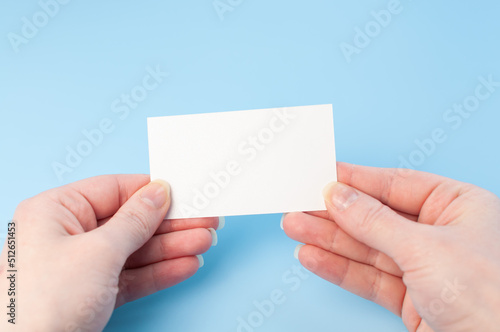 Female hands with a blank card isolated on blue background. Hands with empty white card. Mock up