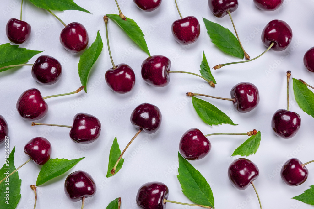 background of ripe cherries with water drops on white background with green leaves close-up top view background of ripe cherries with water drops on white background with green leaves close-up top view