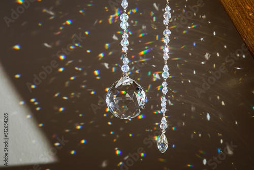 Selective focus on ball and teardrop shape crystal rainbow maker suncatcher hanging in home. Good Feng Shui, Sha Chi energy flow concept. Beautiful spring light in room. photo