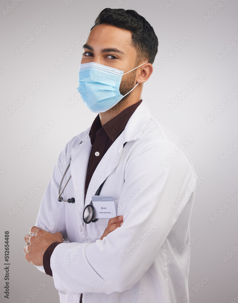 You better be following Covid rules. Shot of a handsome young doctor standing alone in the studio with his arms folded and wearing a face mask. You better be following Covid rules. Shot of a handsome young doctor standing alone in the studio with his arms folded and wearing a face mask.