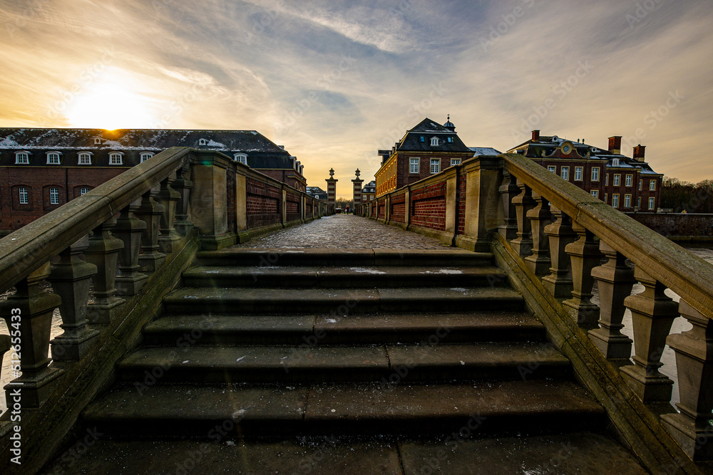 view of an old, well-preserved castle in germany across the steps of a small bridge