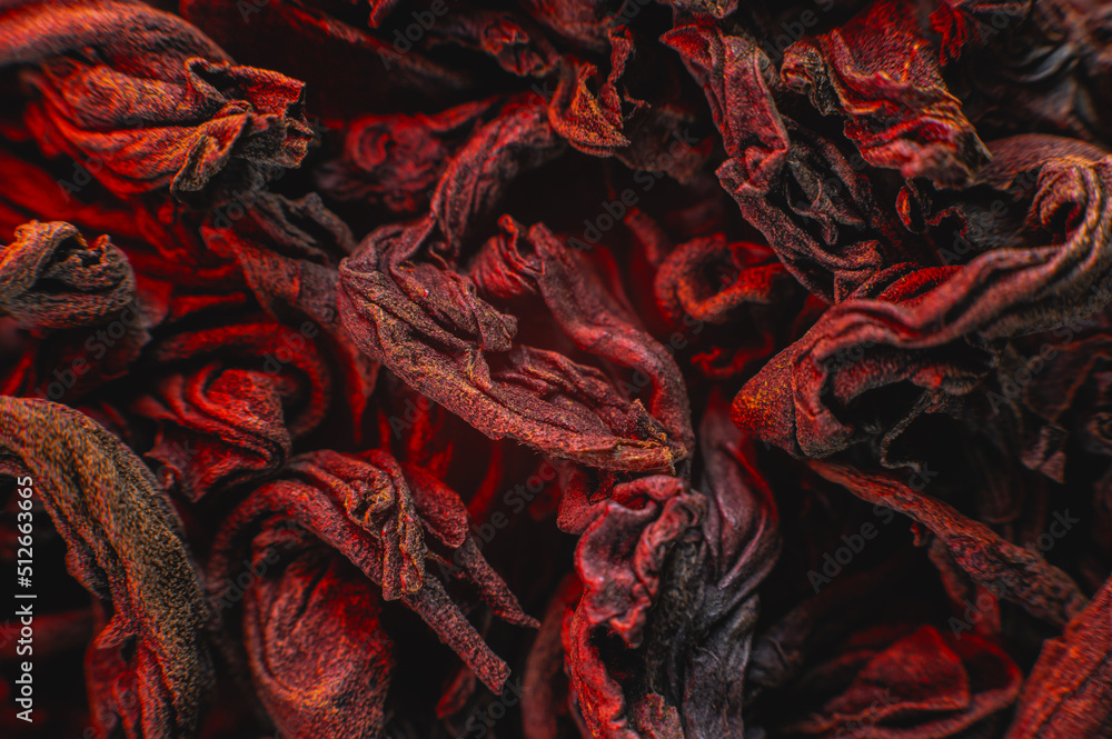 Obraz premium Dry black tea leaves close up. Macro background of tea production on a red light