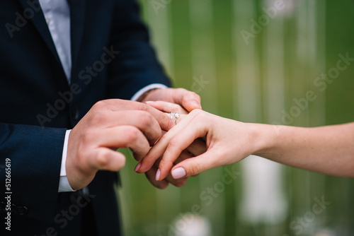 On the wedding day, the bride puts an engagement ring on the groom's finger.