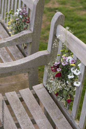 Bunch of memorial flowers attached to a wooden park bench. © Mark