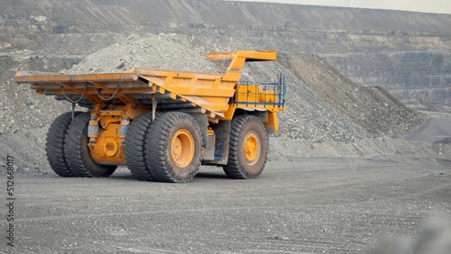 Close-up of dump truck moving on a quarry road loaded with ore. Back view.