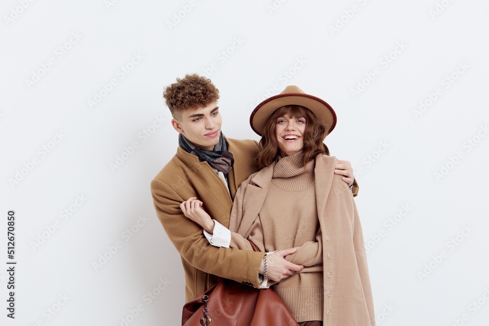 a beautiful, loving couple of a man and a woman stand on a white background in stylish autumn clothes, gently embracing and the woman happily looks at the camera, and the man at her a beautiful, loving couple of a man and a woman stand on a white background in stylish autumn clothes, gently embracing and the woman happily looks at the camera, and the man at her