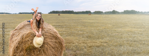 Girl and haystack. Beautiful blonde woman lying on a haystack in field and smiling, copy space. Banner photo