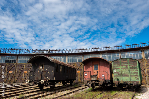 Old cargo cars standing outside of historic locomotive shed. The shot was taken in natural lighting conditions ....