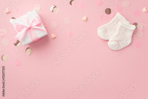 Gender party concept. Top view photo of white giftbox with bow small hearts tiny socks and shiny confetti on isolated pastel pink background with empty space