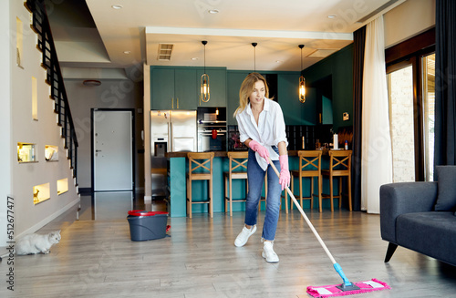 A young woman diligently cleaning the floor at home with a mop