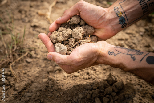 Man hands holding dry soil on a field