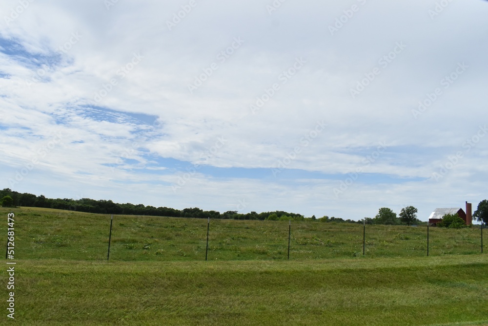 Fototapeta premium Farm Field Under a Blue Cloudy Sky