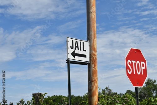 Sign Pointing to a Jail Next to a Stop Sign