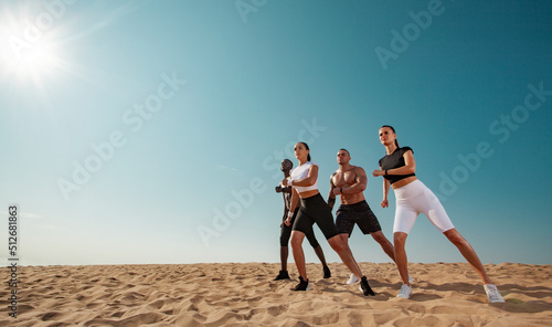 Zumba dancing. Team fitness and sport concept. Group of four young sportsmens women and men, fit athletes are standing on the sky background.