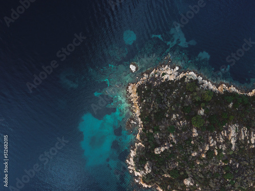 Drone view above small island with green vegetation and rocky coastline in the Mediterranean at Chalkidiki peninsula, Greece.