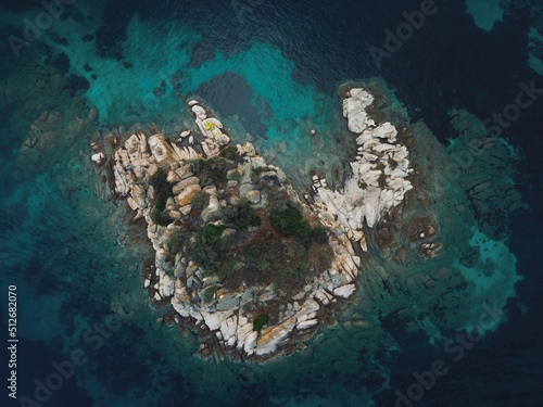 Drone view above small rocky island with green vegetation in the Mediterranean at Chalkidiki peninsula, Greece
