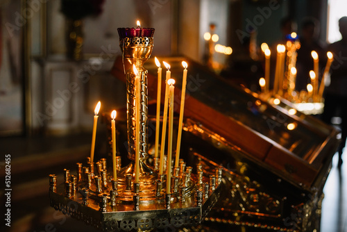 Many candles burn in the Orthodox Church. Element of the russian, ukrainian rite: wedding, funeral, christening. Parishioners of the church are in blur. Religious room for prayer. High quality photo.