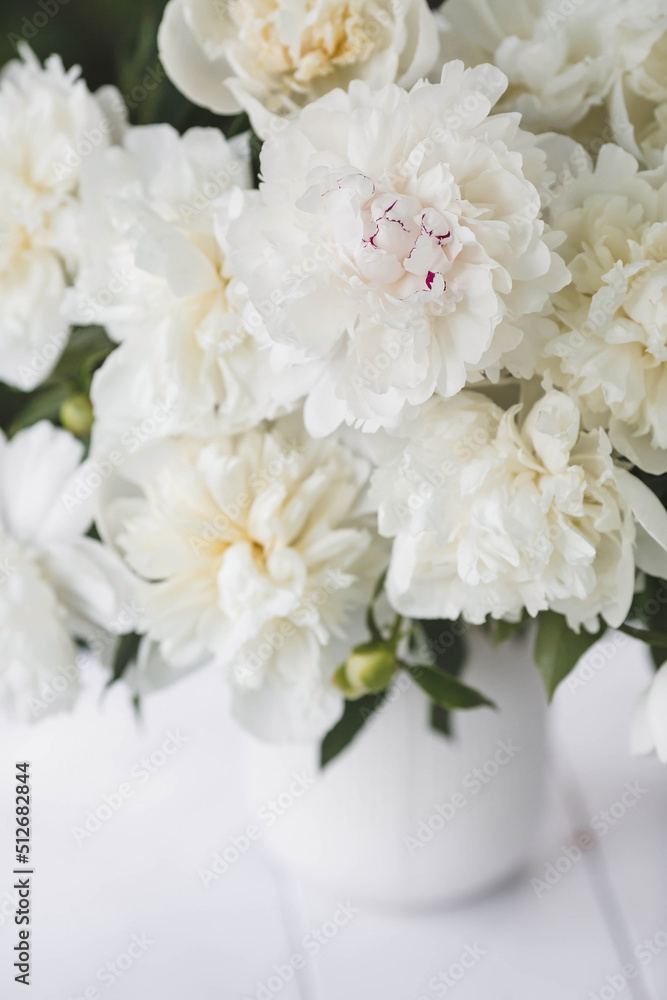 Beautiful white bouquet of peonies in a white vase on a white wooden background. Close-up. Flowers and buds. Beautiful white bouquet of peonies in a white vase on a white wooden background. Close-up. Flowers and buds.