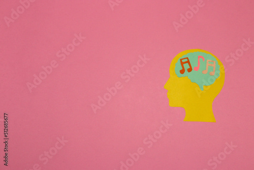 yellow head with a brain with notes, listening to music, pink background with copy space, creative modern design