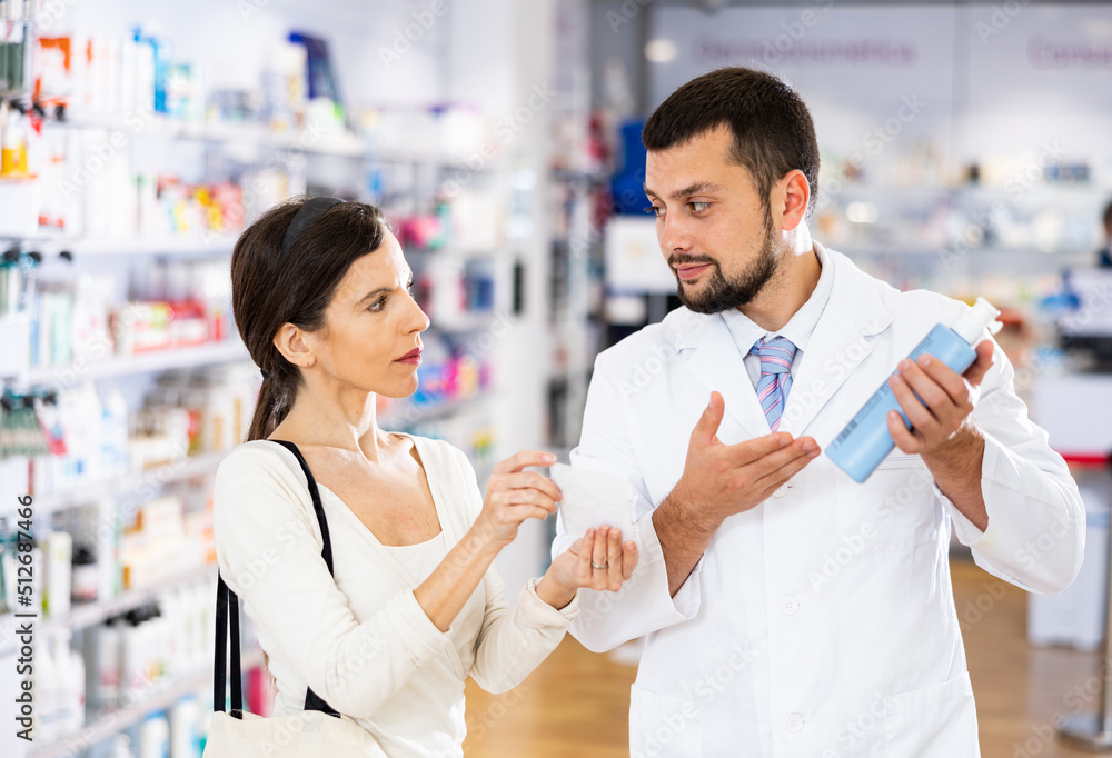 Male pharmacist consulting woman buyer about hair care product in drugstore.