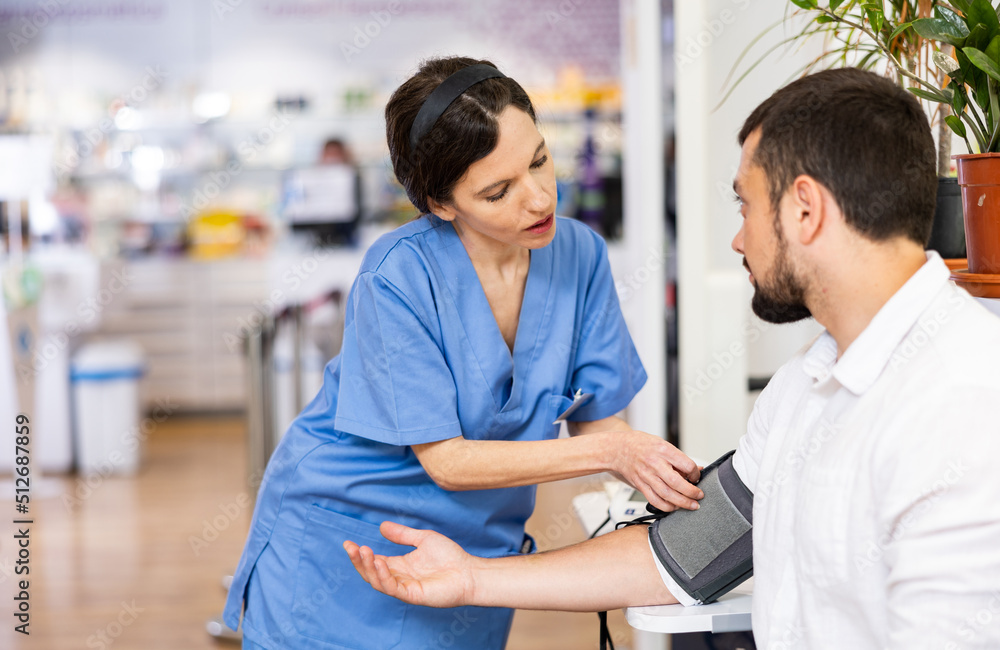 Obraz premium Pharmacist measures arterial blood pressure with a tonometer in a man