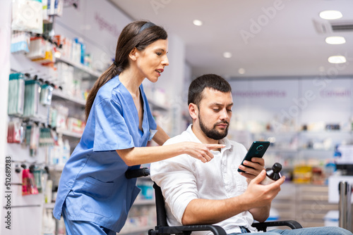 Woman pharmacist helping man in wheelchair to help choose medicine in pharmacy